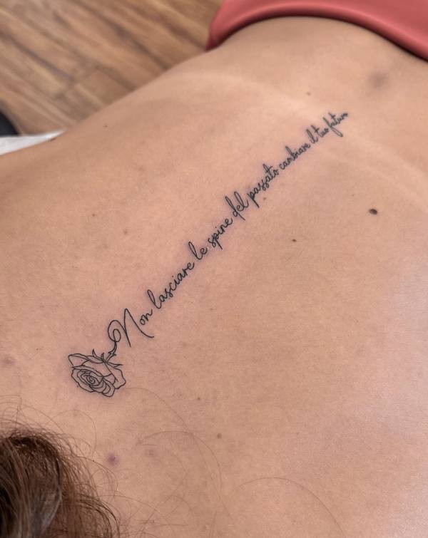 Italian script quote with rose fine line back tattoo by Cihan Pohrenk in Venice, Los Angeles