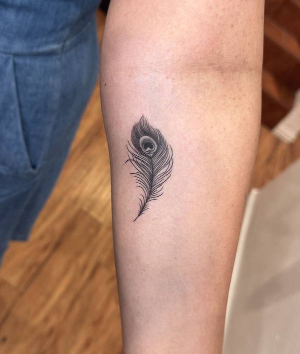 Peacock feather fine line forearm tattoo by Cihan Pohrenk in Venice, Los Angeles