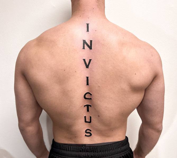 INVICTUS vertical script spine tattoo by Cihan Pohrenk in Venice, Los Angeles