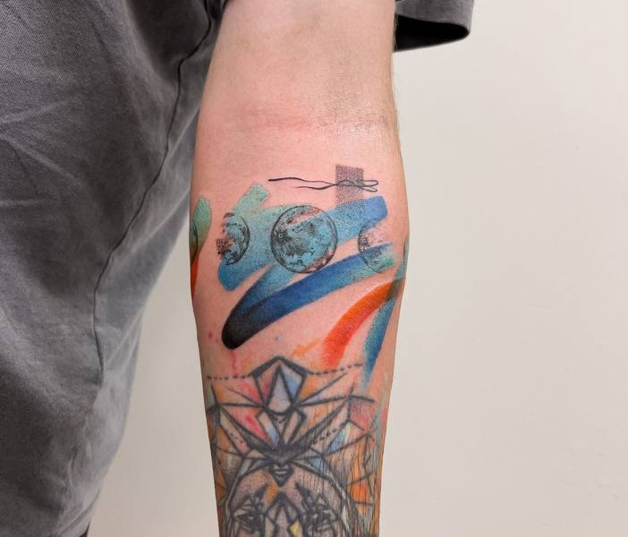 Abstract brushstroke with planets color forearm tattoo by Cihan Pohrenk
